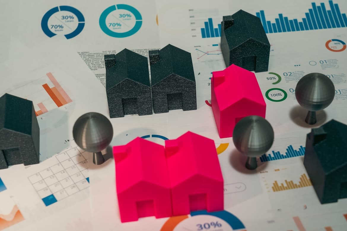 Maquetas arquitectónicas de viviendas sobre análisis financiero de mercado inmobiliario.